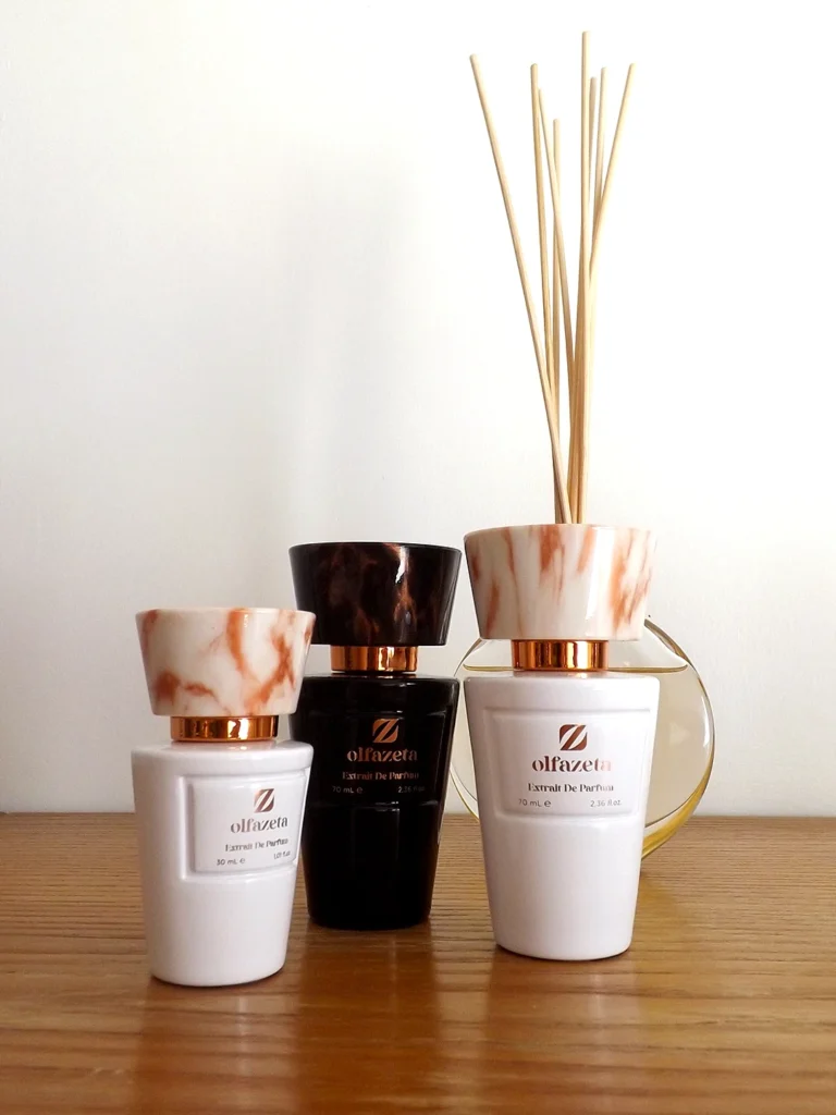 Trois flacons de parfums Chogan de la gamme Olfazeta dans 2 formats différents posés sur une belle commode en bois.
