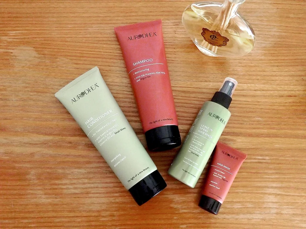 Quatre produits de soin pour les cheveux Chogan de la gamme Aurodhea, posés sur une commode en bois.